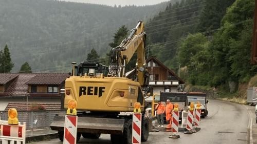 Baustelle in der Landstraße mit Bagger und Absperrungen